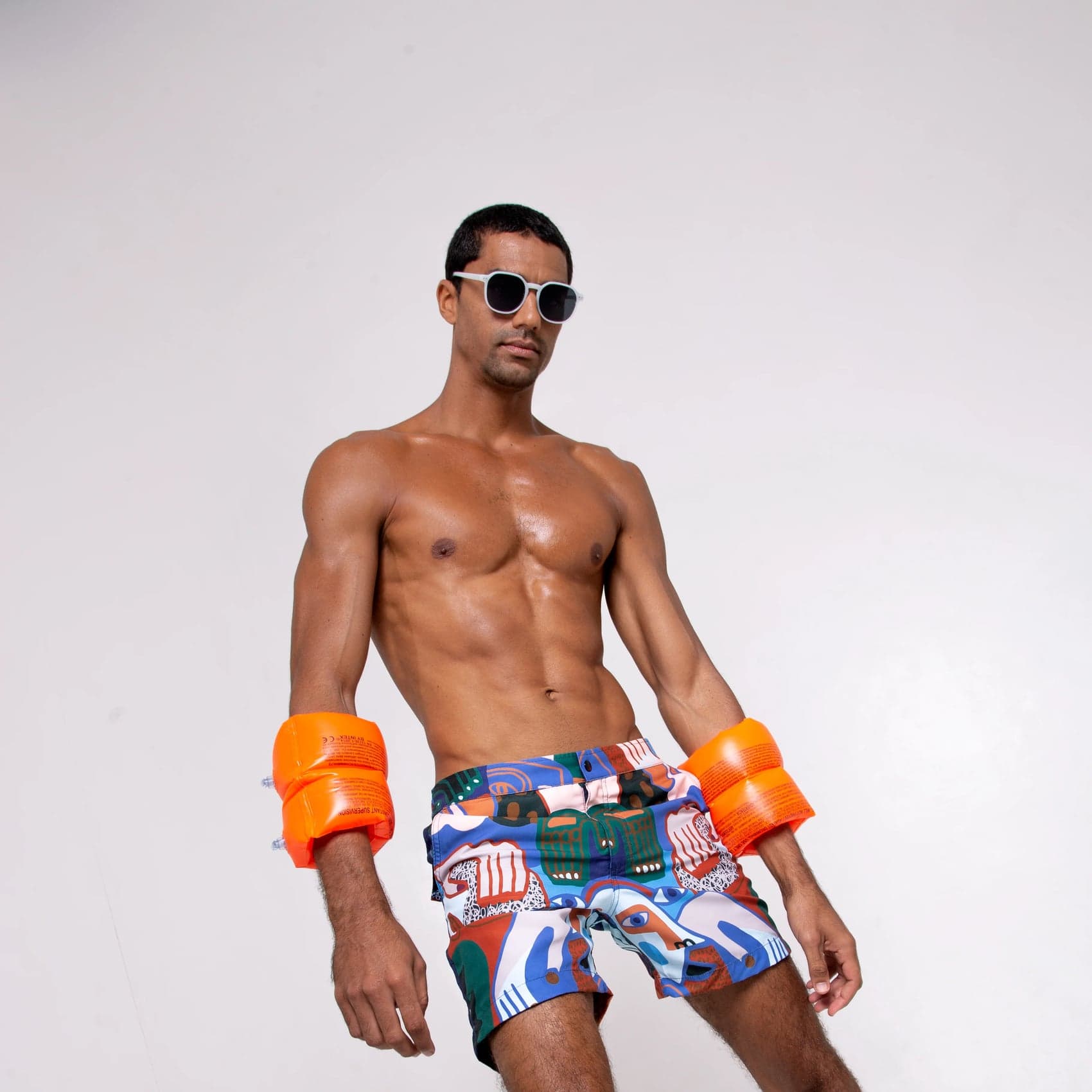 Model wearing the Sama Sama swim shorts with orange armbands