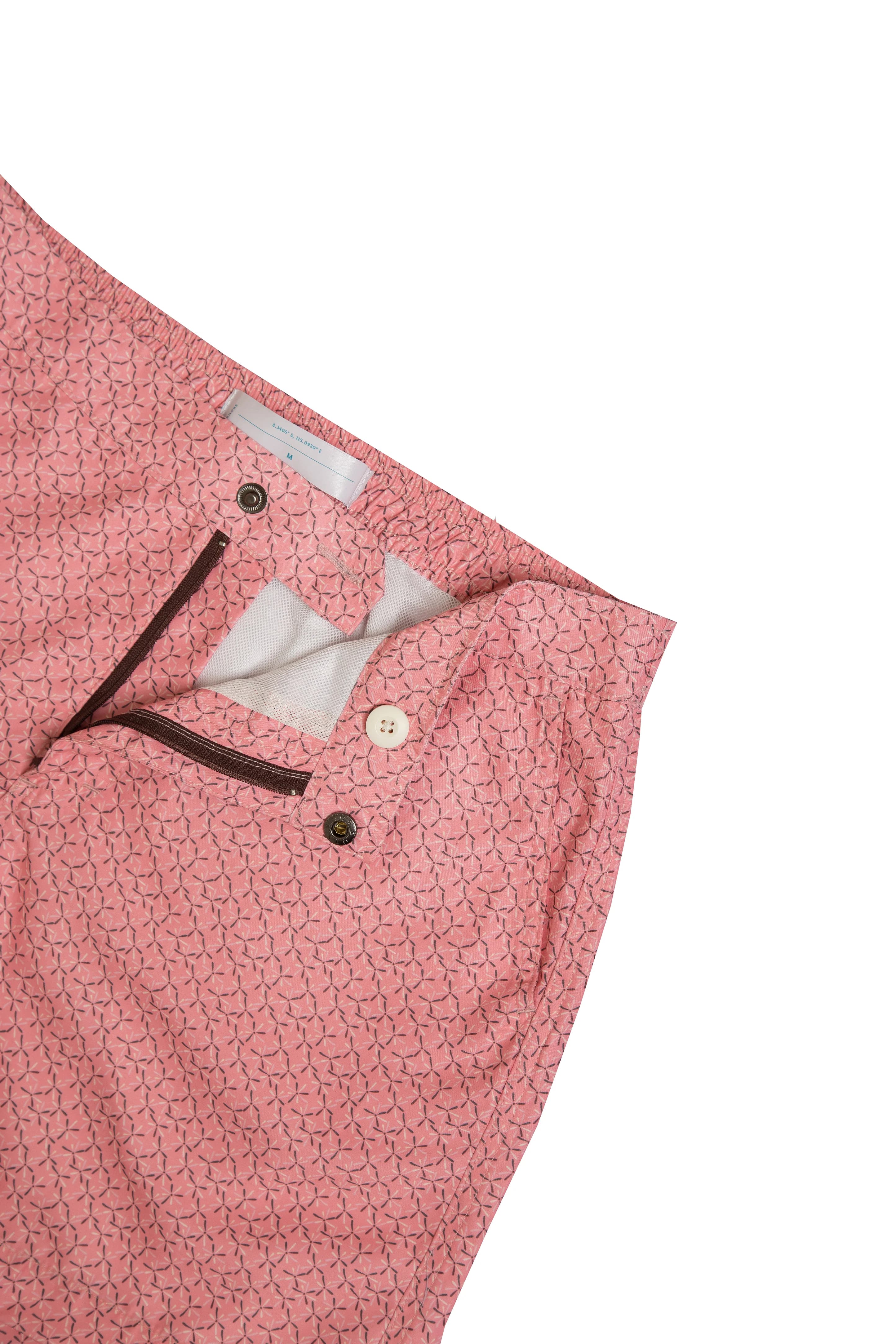 Pink swim shorts laid flat, the fly open to show the inner label