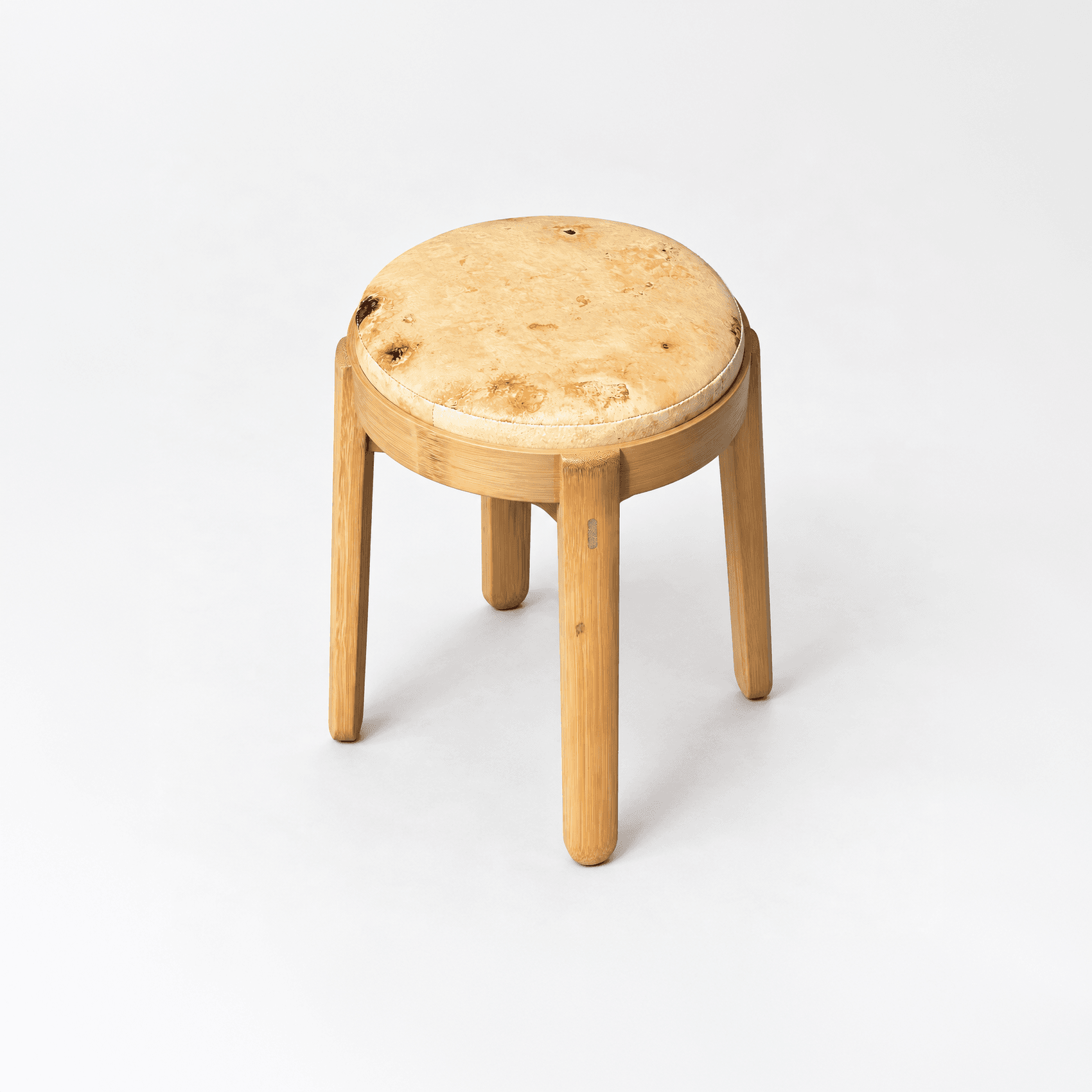 A stool with a mottled mycelium seat set in a bamboo ring