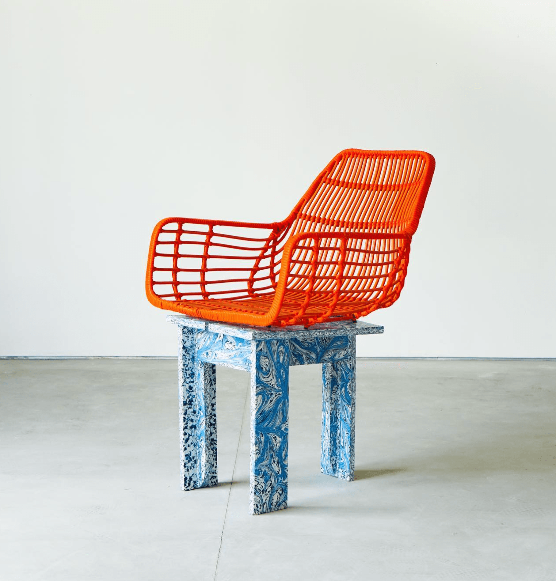 An orange woven chair on a base of marbled blue recycled plastic panels